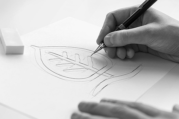 Hand sketching a leaf logo design with pencil on white paper