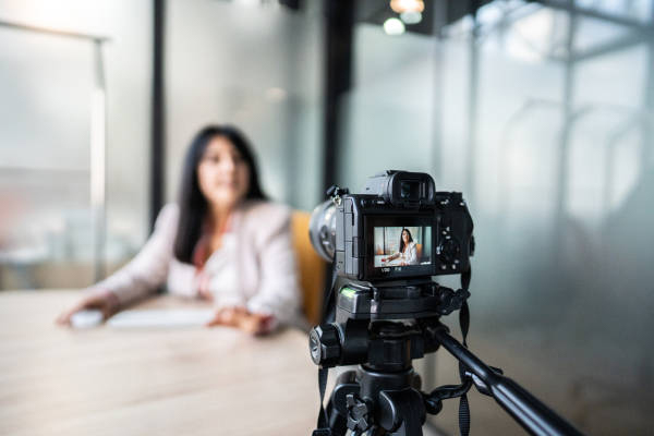 Professional DSLR camera on tripod recording a woman in a studio setting